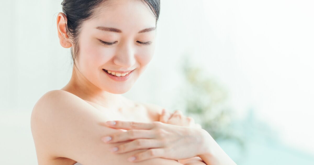 肩に触れて微笑む女性 上半身 クローズアップ 美肌