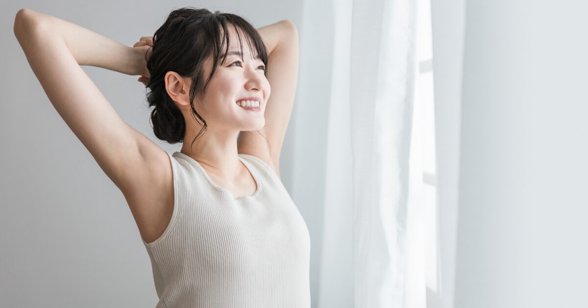 室内で腕を上げて伸びをする女性 リラックス 美容
