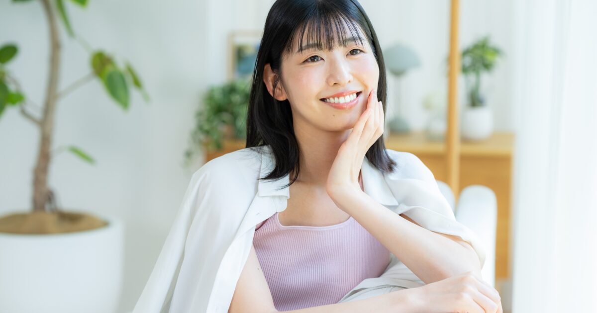 室内で頬に手を当てて微笑む女性 スキンケア 美容