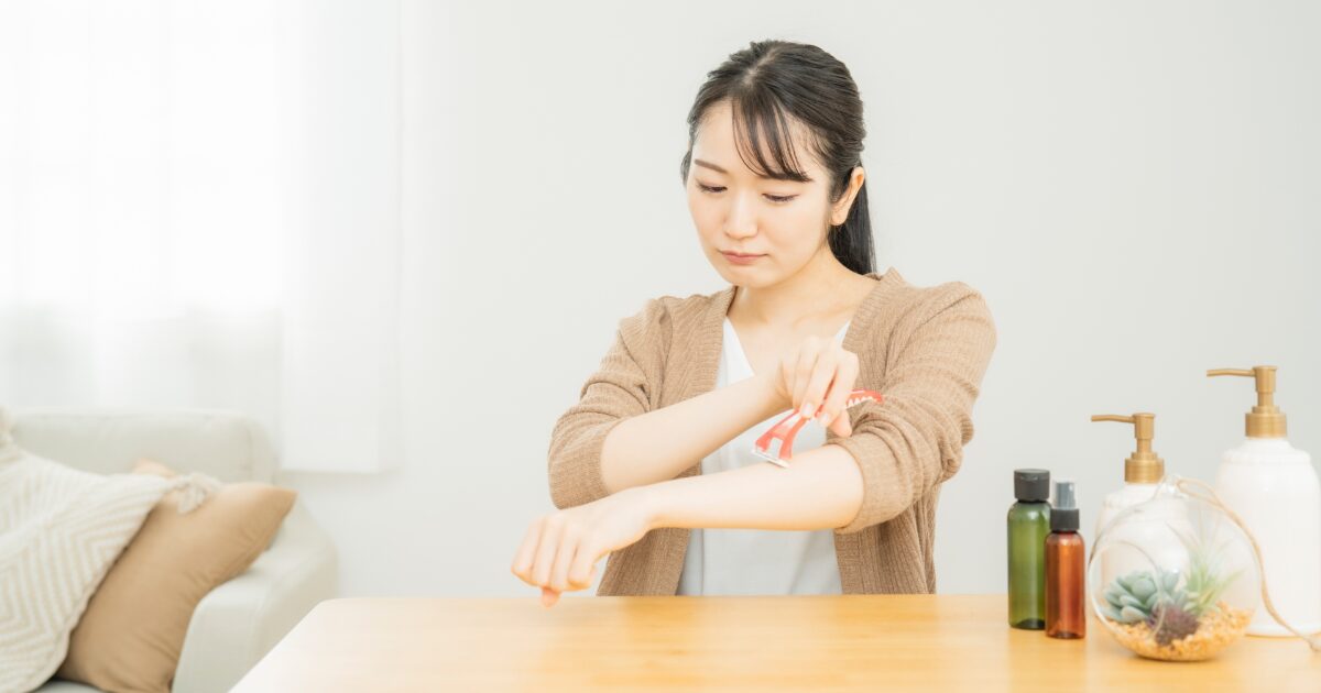 自宅で腕のムダ毛処理をする女性 スキンケア用品 テーブル