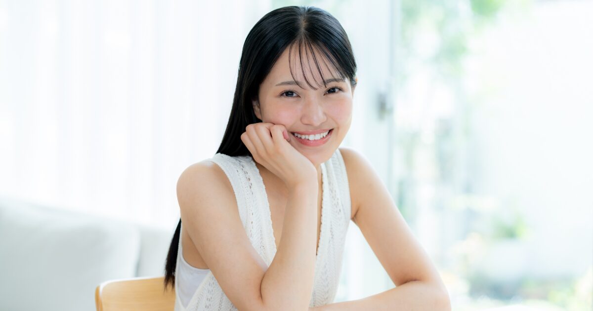 室内で頬に手を当てて微笑む女性 ナチュラルメイク 美肌