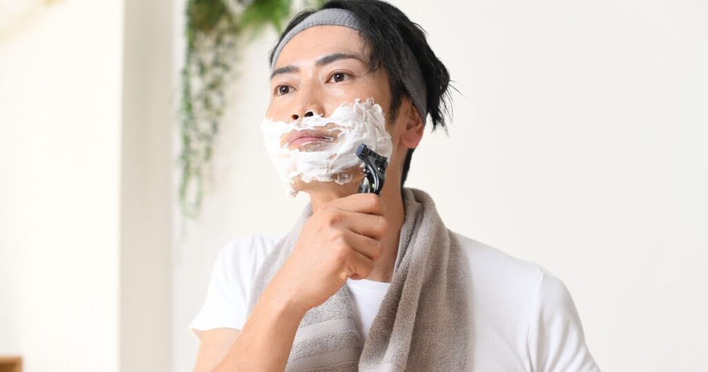 シェービングフォームを使って髭を剃る男性