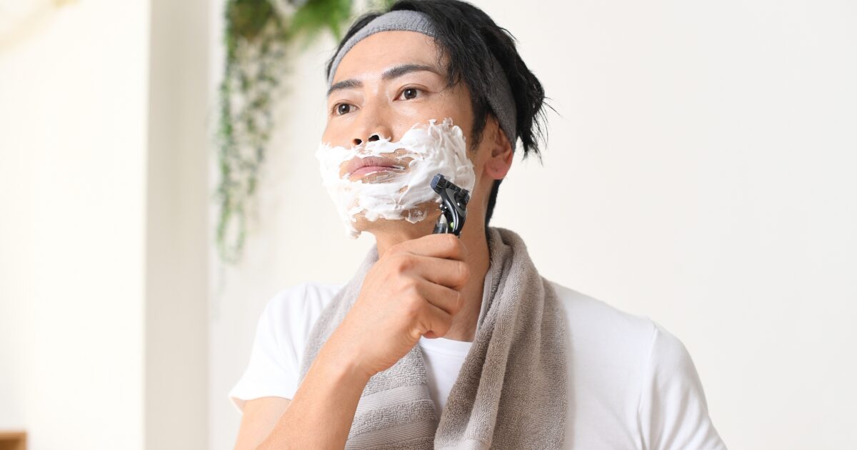 シェービングフォームを使って髭を剃る男性