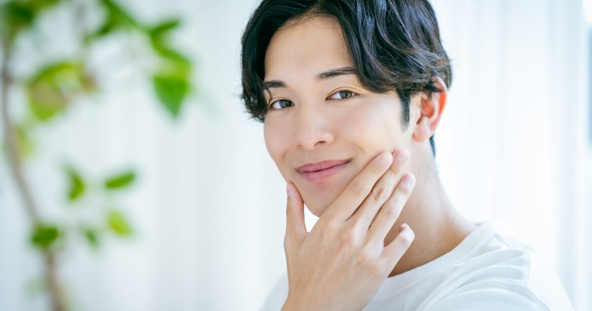 肌に触れてうるおいを確認する笑顔の男性