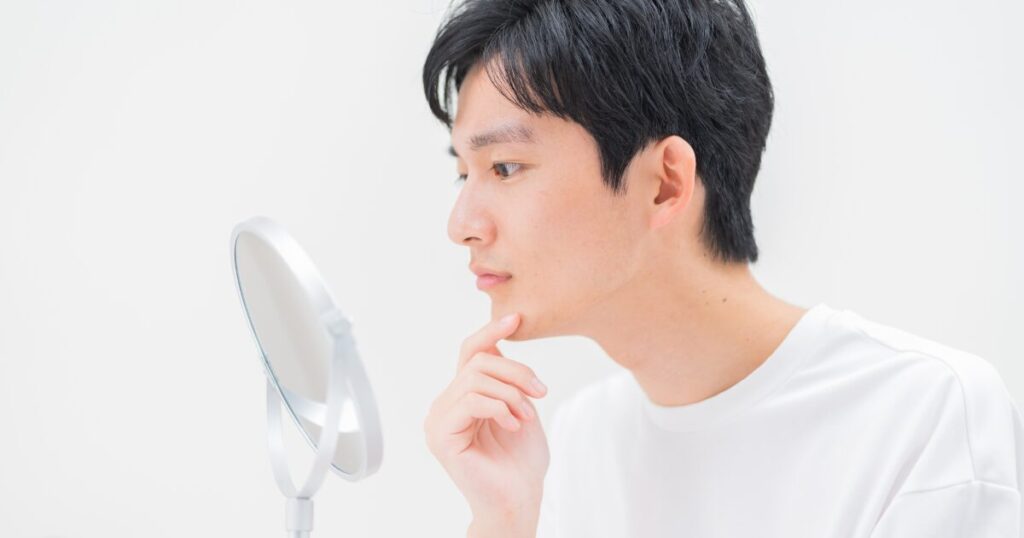 手鏡でフェイスラインを確認する男性の横顔