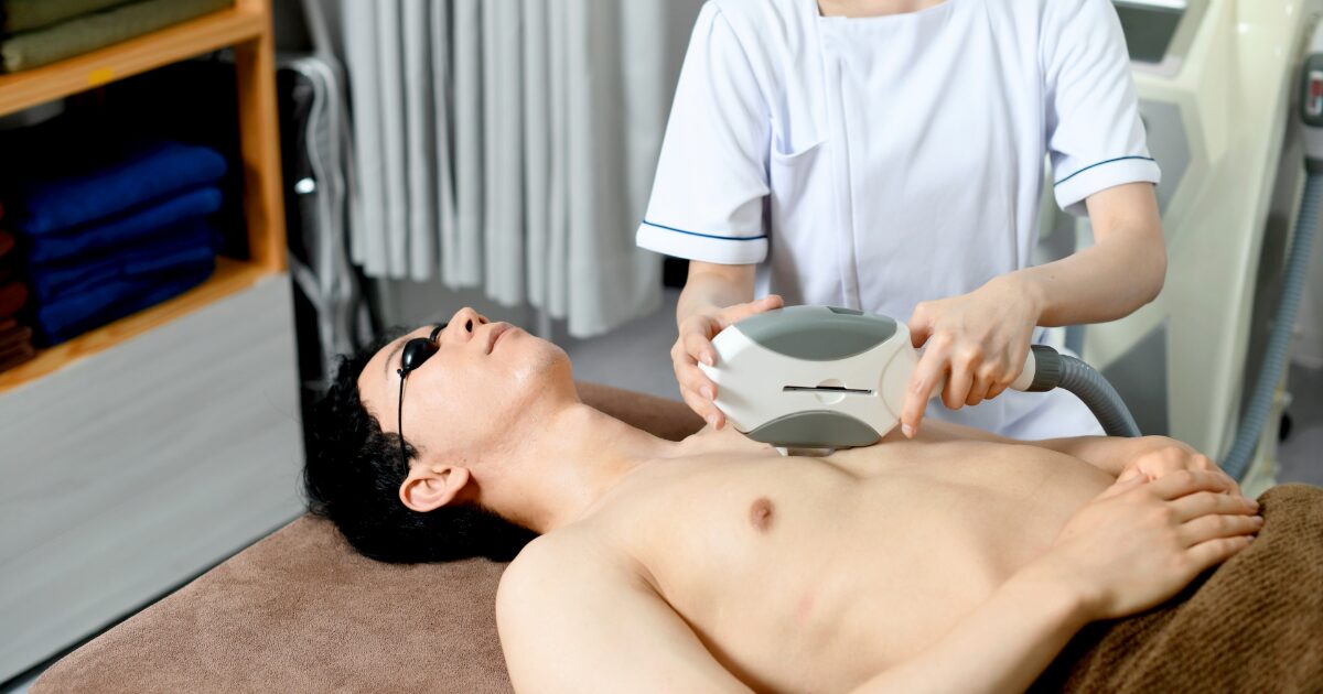 胸のムダ毛を脱毛機でケアする男性
