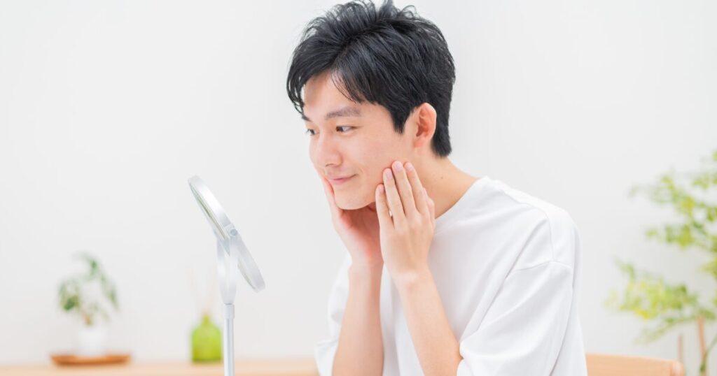 鏡を見ながらスキンケアをする男性