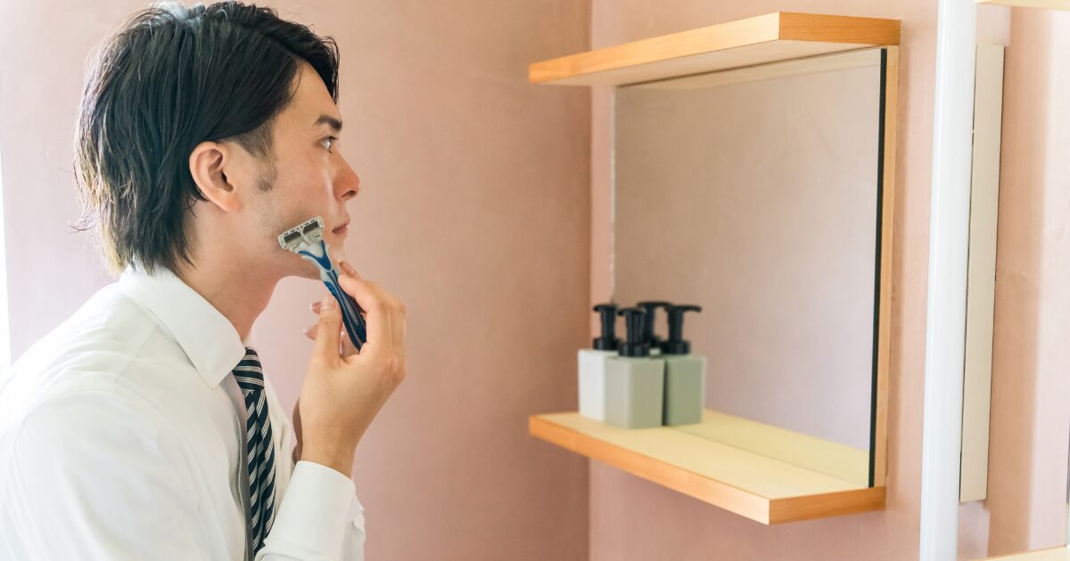洗面所の鏡の前で髭剃りをするビジネスマン